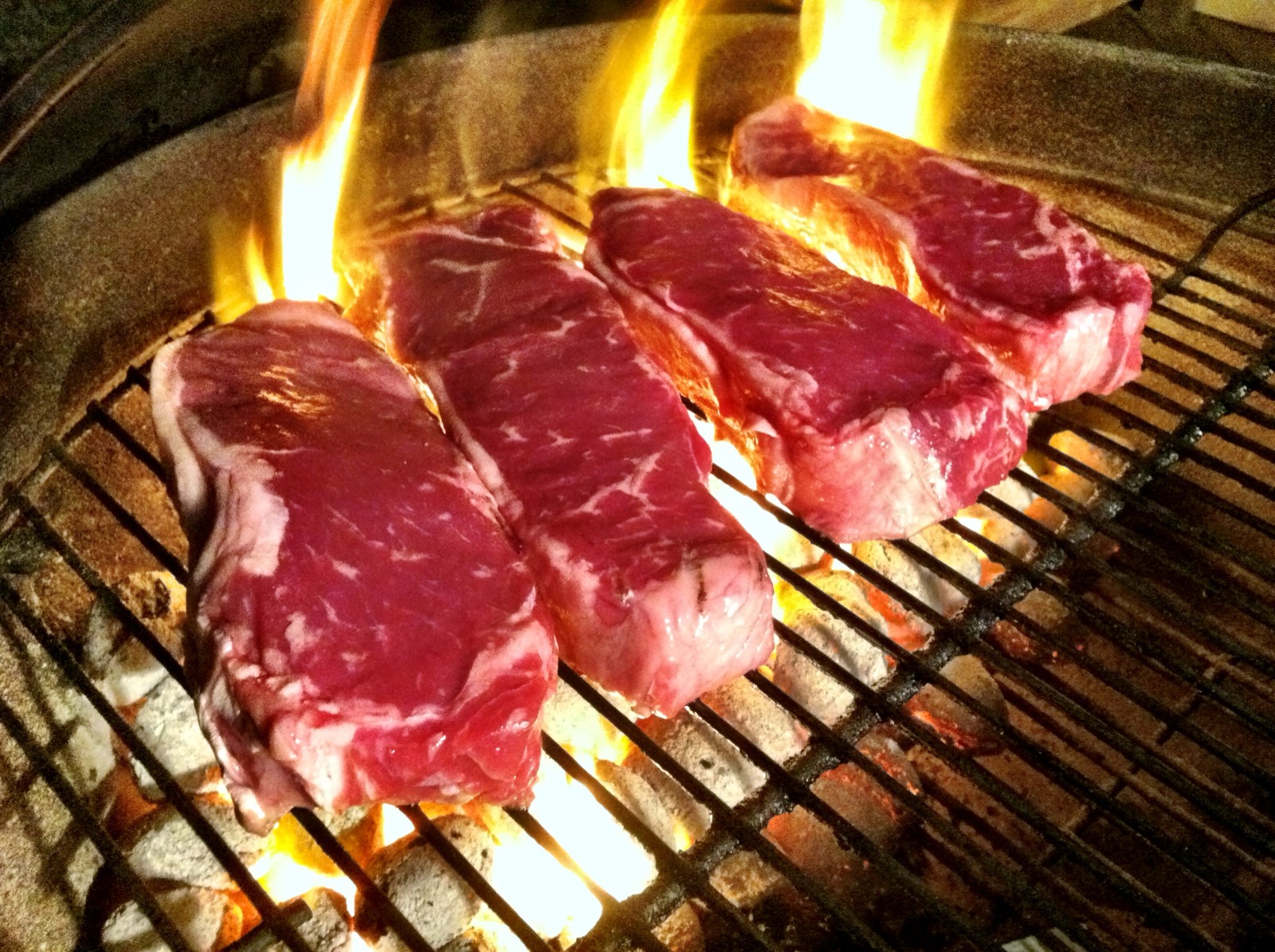 Meat cooking over open grill flames