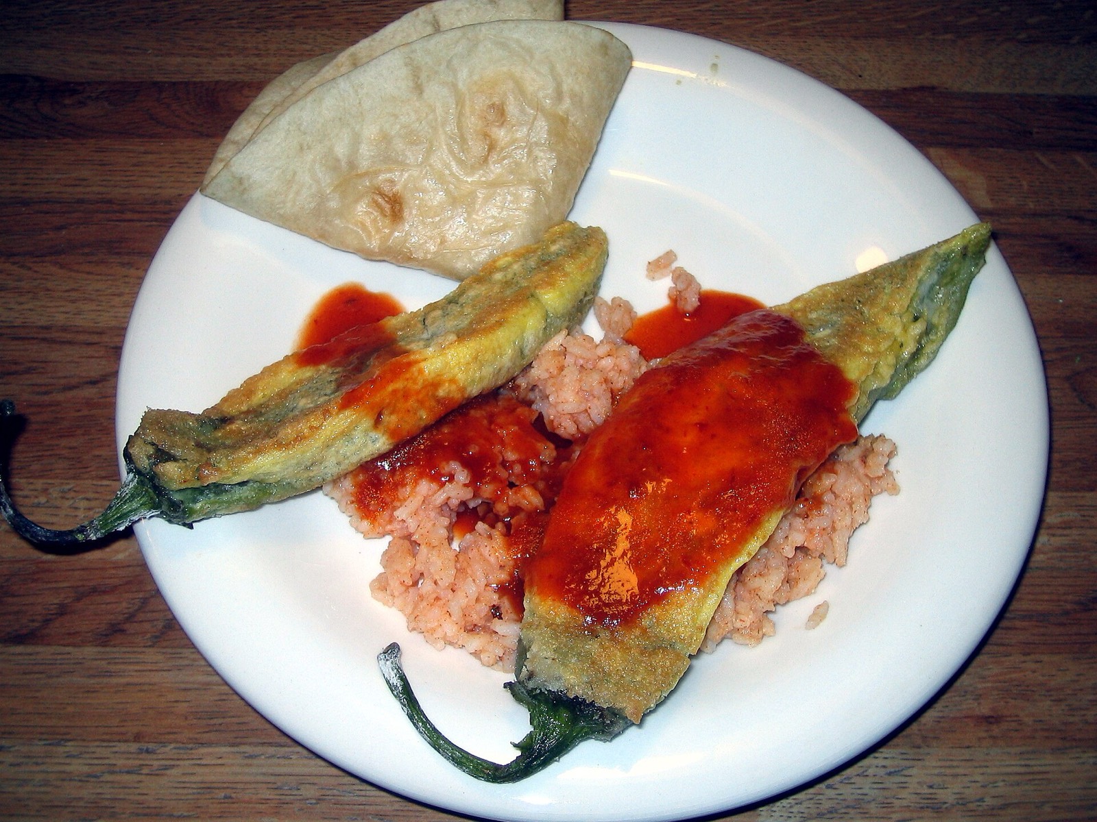 A chile relleno in egg batter with red sauce